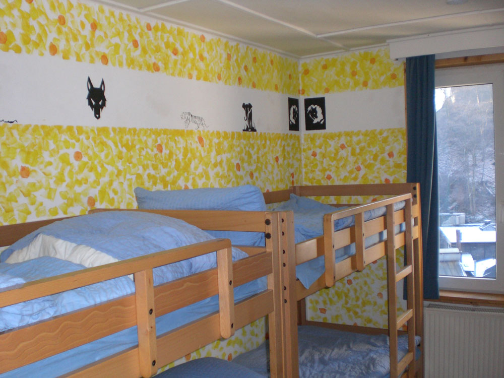 Das Bild zeigt zwei Doppelstockbetten eines Zimmers mit Bildern an der Wand