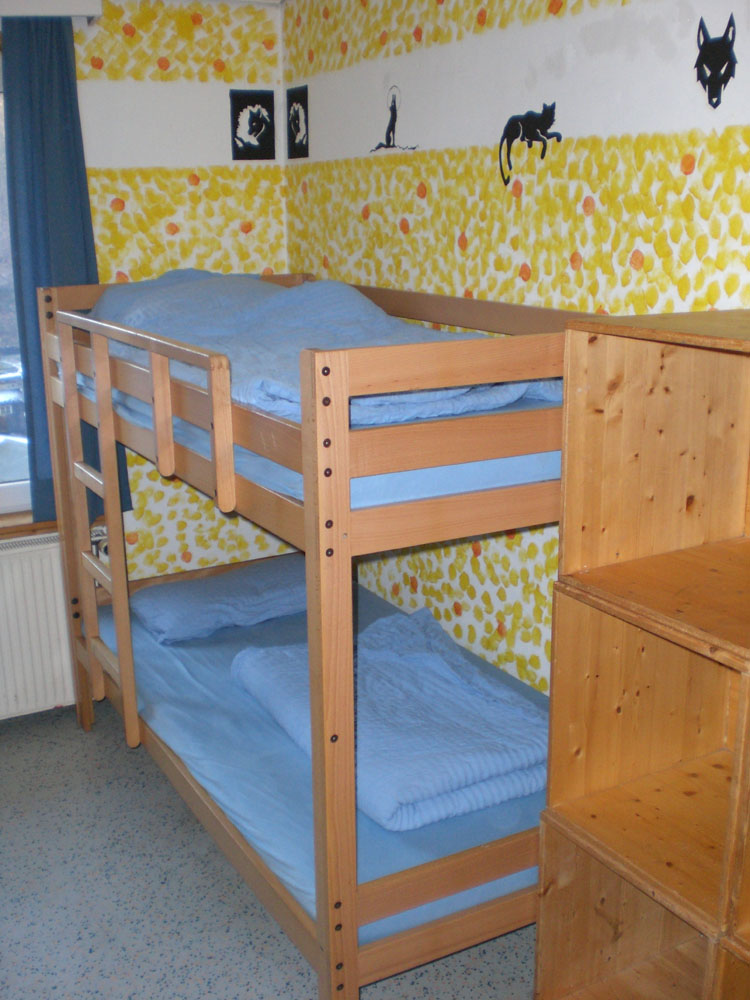 Das Bild zeigt ein Doppelstockbett eines Zimmers mit Bildern an der Wand